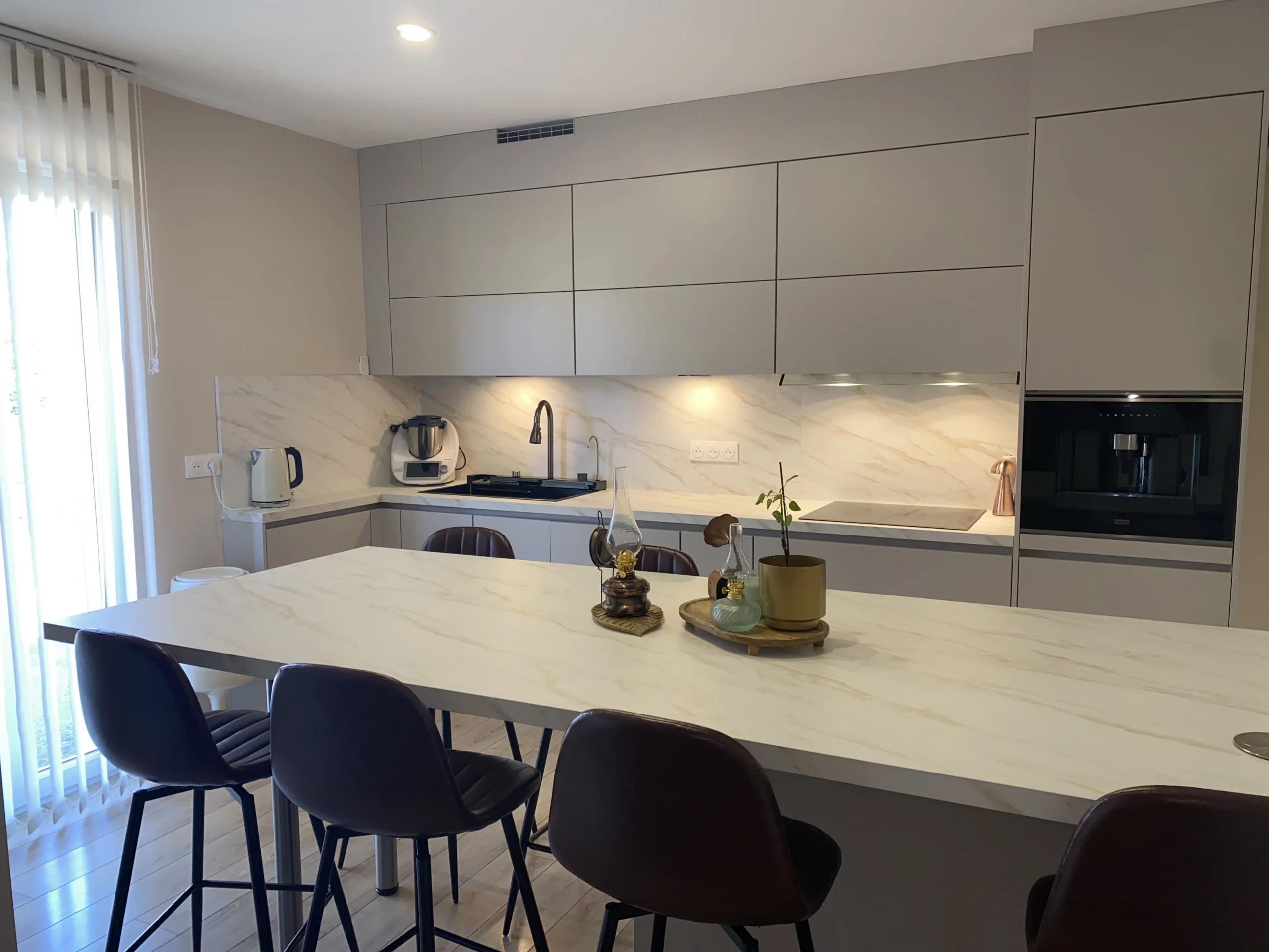Réalisation client d'une cuisine grise en L avec îlot central marbre et crédence assortie, signée KOA Kitchen à Remiremont