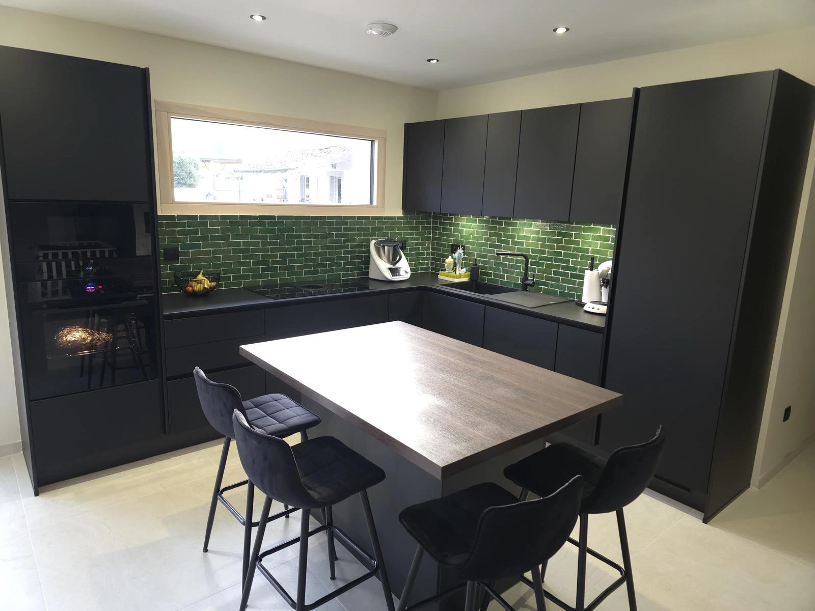 Réalisation client d'une cuisine noire mat avec îlot central en bois et plan de travail noir, signée KOA Kitchen dans les Vosges