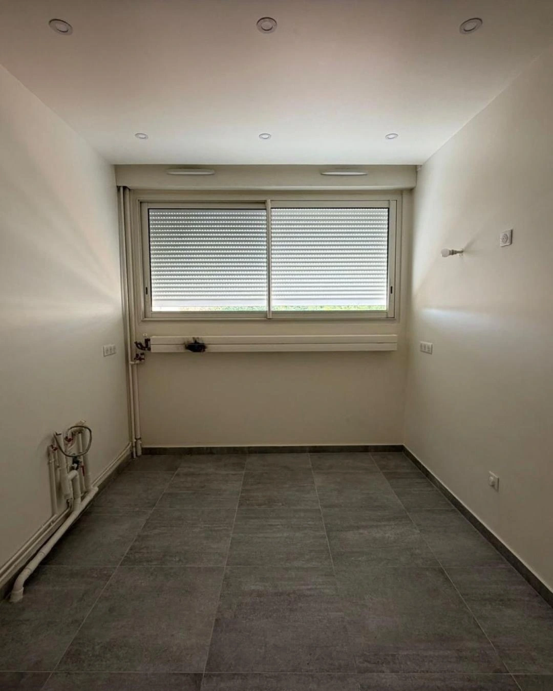 Pièce carrelée gris vide avant aménagement d'une cuisine sur mesure