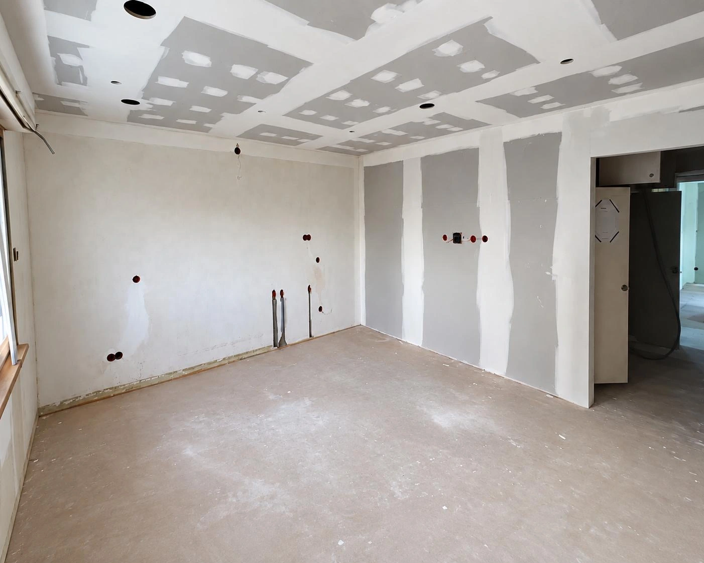 Pièce avant rénovation : sol mis à nu et murs à reprendre, avant la pose d'une cuisine sur mesure