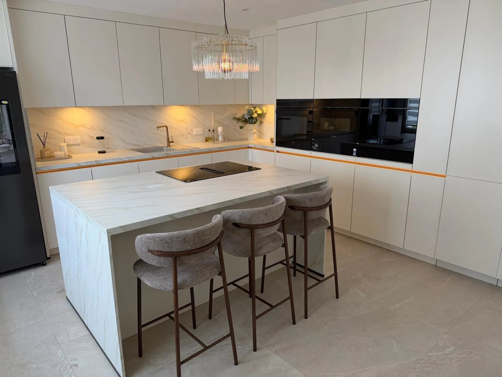 Îlot central effet marbre avec plaque de cuisson et tabourets de bar, cuisine haut de gamme sur mesure